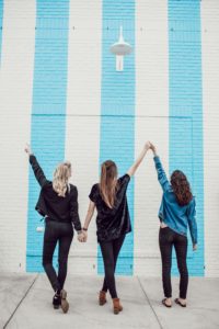Image of three friends standing in front of a blue-white wall