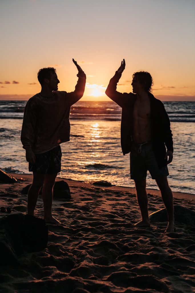 Two friends highfiving on a beach